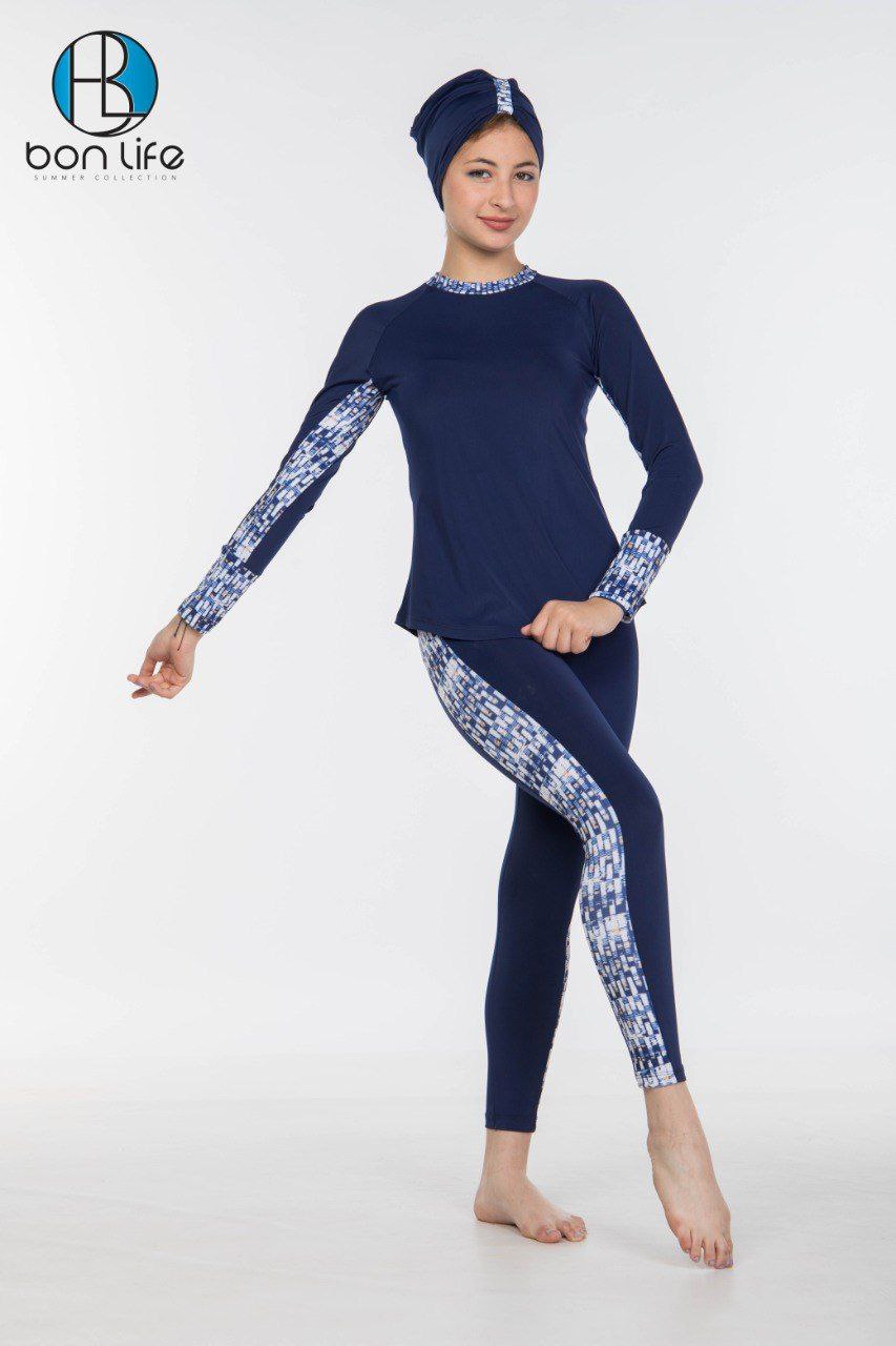 Person wearing a navy blue swimsuit with white floral patterns and matching headscarf on a white background.