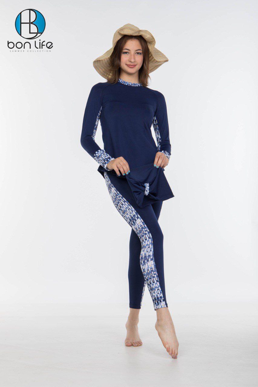Woman wearing a navy blue swimsuit with white patterns on a white background, with 'bon life' branding.