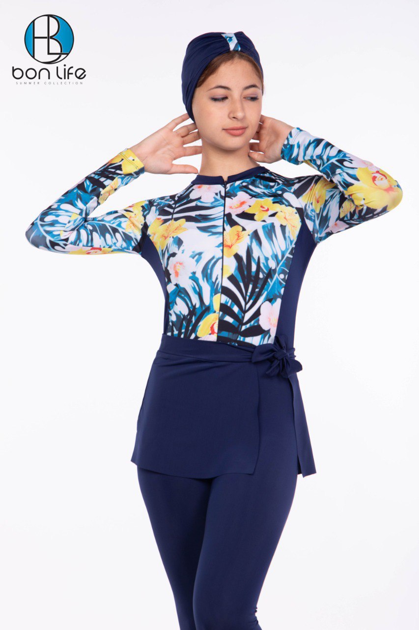 Woman wearing a colorful floral swimsuit with a navy blue hijab and pants on a white background, featuring the brand 'bon life'.